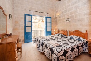 A bedroom with a wooden bed, a dresser, and a blue door leading to a balcony.