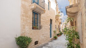 A narrow stone-paved alley with buildings on either side, potted plants, and a clear sky. - 3 Bedrooms House of Character in Rabat Near Mdina - Casa Melita (Rabat)