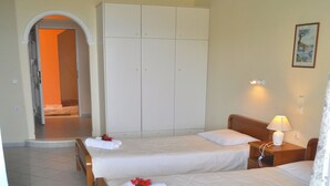 Hotelkamer met twee bedden, een kledingkast, een nachtkastje met lamp en een schilderij aan de muur.