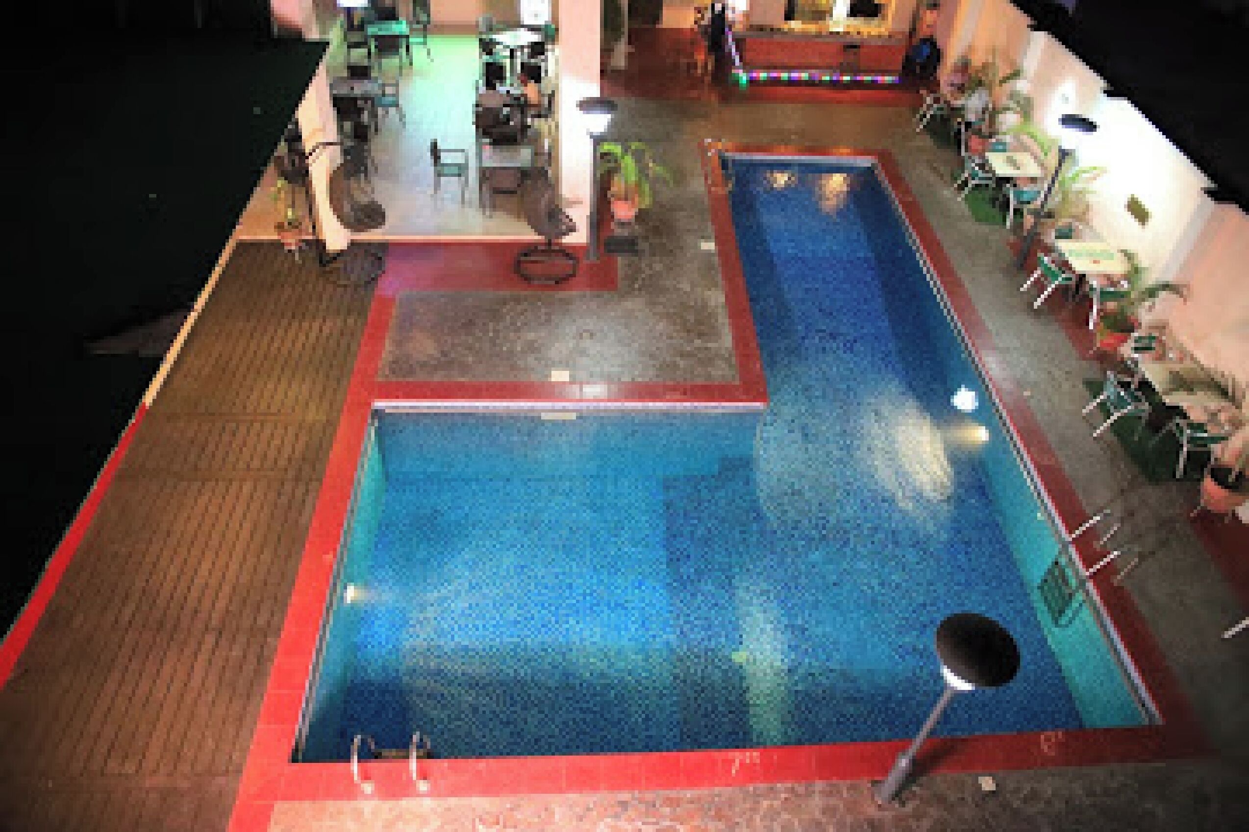 Un área de piscina con dos piscinas, sillones de descanso y mesas.