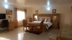 A hotel room with a bed, desk, chair, and a TV. - Room-ayalla Hotel-business Suite (Port Harcourt)