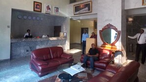 A lobby with a reception desk, a large mirror, red leather sofas, and a marble floor. - Room-ayalla Hotel-business Suite (Port Harcourt)