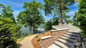 Un escalier en pierre mène à une terrasse aménagée avec des sièges, d’où l’on a vue sur un lac.