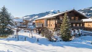 A wooden chalet with a balcony, surrounded by snow-covered trees and mountains in the background. - Holiday home on a former stables (Brixen im Thale)