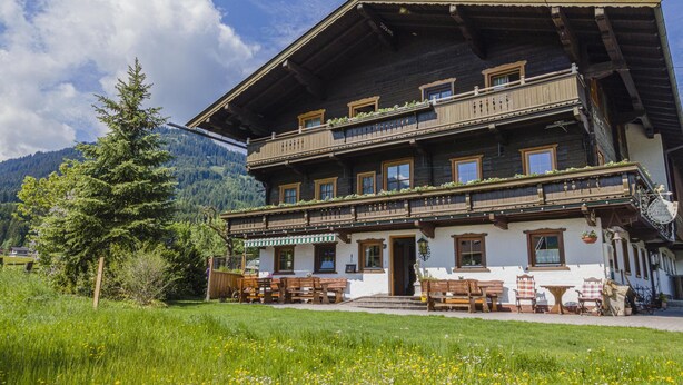 A traditional chalet with a wooden facade, multiple balconies, and a garden area with outdoor seating. - Holiday home on a former stables (Brixen im Thale)