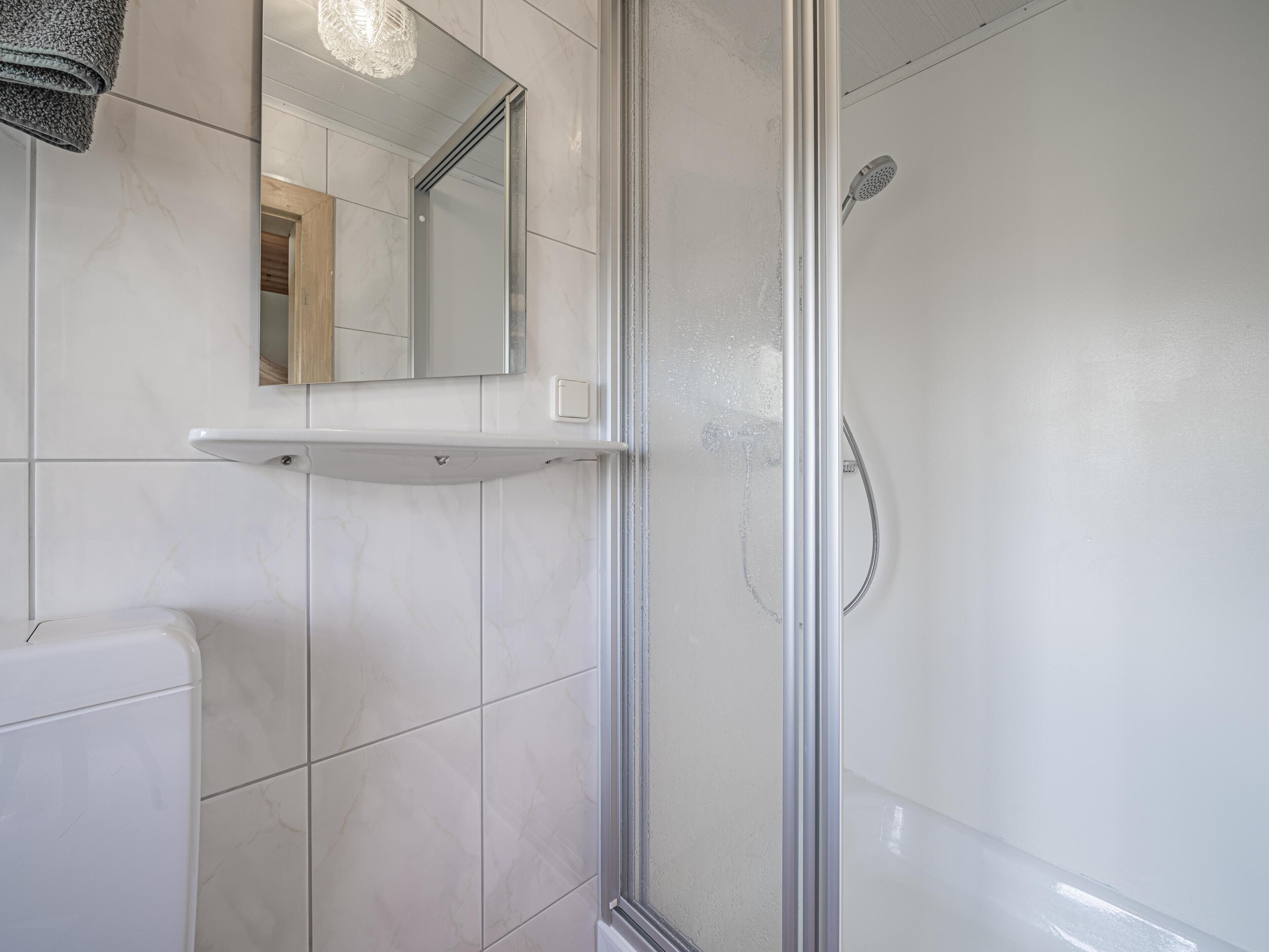 A modern bathroom with a glass-enclosed shower, a white toilet, and a mirror above the sink.