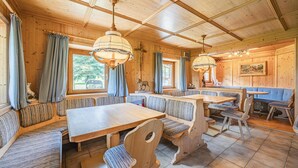 A wooden interior with a long dining table and benches, large windows, and a ceiling with a grid pattern. - Holiday home on a former stables (Brixen im Thale)