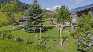 A rural setting with a wooden swing set, a fenced area, and a building with a sloped roof. - Holiday home on a former stables (Brixen im Thale)