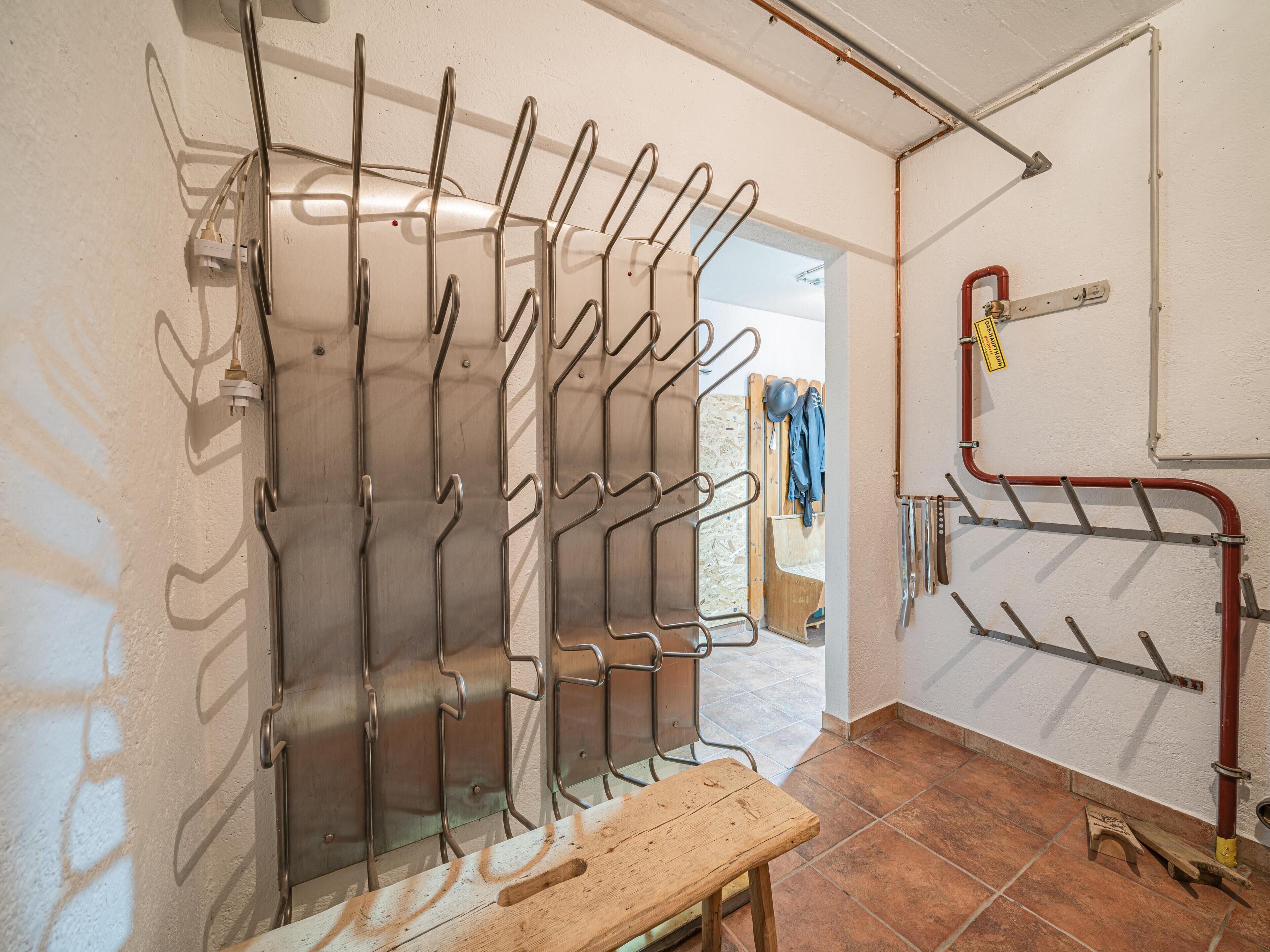 Habitación con un perchero metálico, una banca de madera y piso de baldosas.