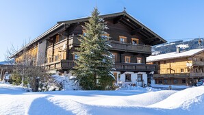 A wooden chalet with a balcony, surrounded by snow-covered ground and a clear blue sky. - Holiday home on a former stables (Brixen im Thale)