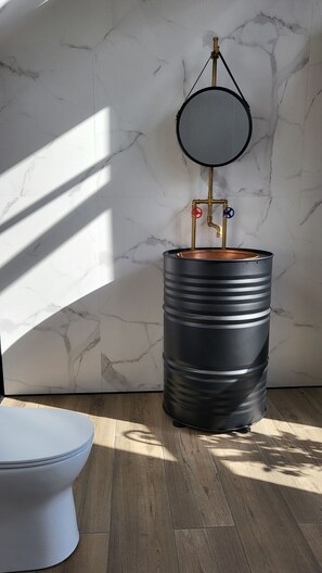 A bathroom with a marble wall, a toilet, and a large black barrel with brass fixtures. - Magnificent View nice double room with shared pool and Ac (Piskopiano)