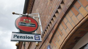 Ein Schild mit der Aufschrift 'Feldschlöbchen' und darunter ein Symbol für ein Pension.