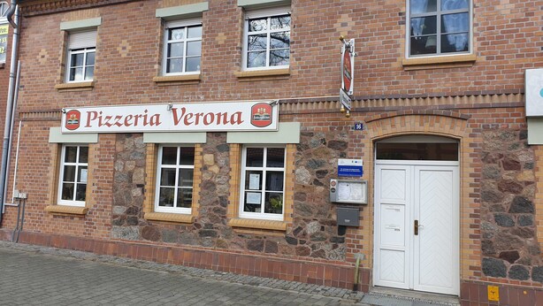Ein Backsteinhaus mit einem Schild für 'Pizzeria Verona'.
