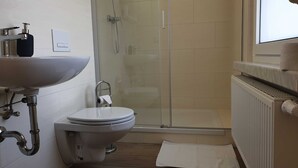 A bathroom with a white sink, toilet, and glass shower enclosure. - Einzelzimmer - Pension Pizzeria Verona (Großräschen)