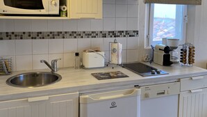Eine kleine Küche mit weißen Schränken, einer Mikrowelle, einem Toaster und einem Geschirrspüler.