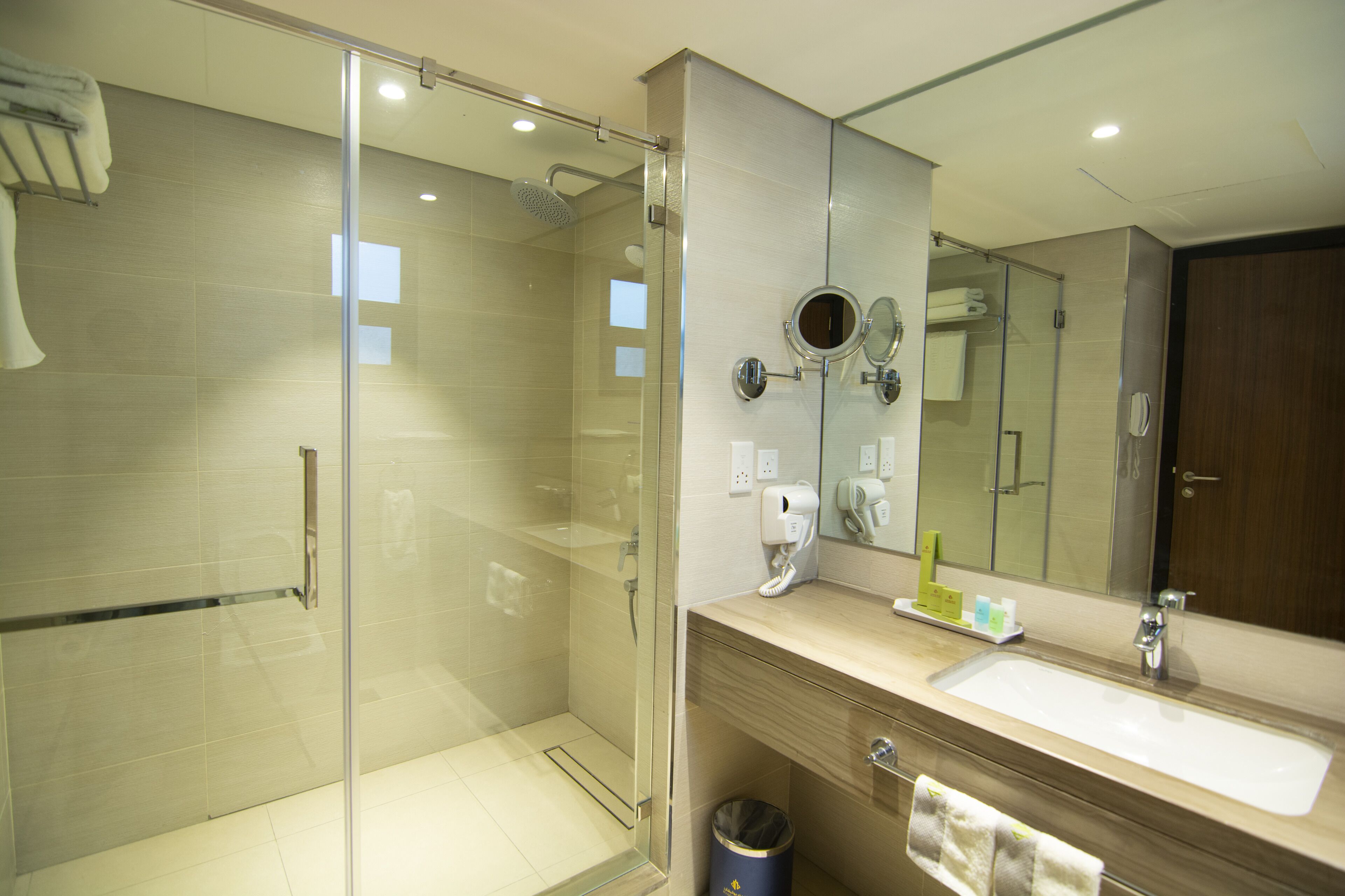 A modern bathroom with a glass-enclosed shower, a sink with a mirror above, and a towel rack.