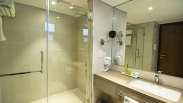 Un baño moderno con ducha de vidrio, un lavamanos con espejo y un perchero para toallas.