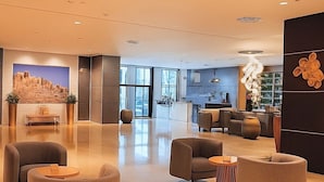 A spacious lobby with modern seating, a reception area, and a large window. - Boulevard hotel (Seeb)