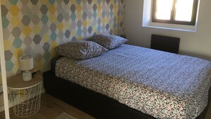 Une chambre à coucher avec un lit, un mur à motifs, une fenêtre et une petite table de chevet avec une lampe.