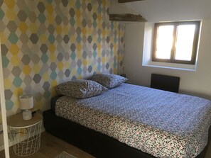 Une chambre à coucher avec un lit, un mur à motifs, une fenêtre et une petite table de chevet avec une lampe.