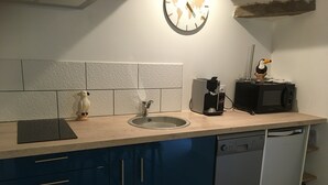 Une cuisine équipée d’un évier, d’une machine à café, d’un four à micro-ondes et d’une horloge murale.