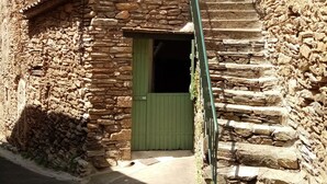 Un bâtiment en pierre avec une porte verte et un escalier menant à un étage supérieur.