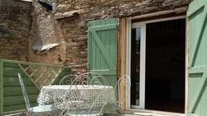 Un bâtiment en pierre avec une porte verte et une table entourée de chaises à l’extérieur.