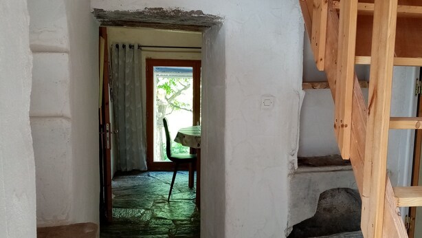 Un escalier étroit, avec des marches en pierre, menant à une porte.