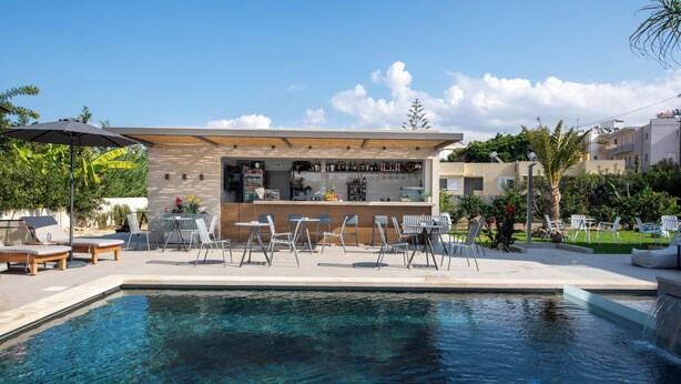Un área de bar moderna al aire libre con piscina, mostrador y asientos.