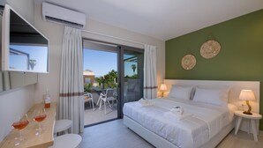 Habitación de hotel con cama, una mesa con dos copas de vino, una silla y vistas al exterior.