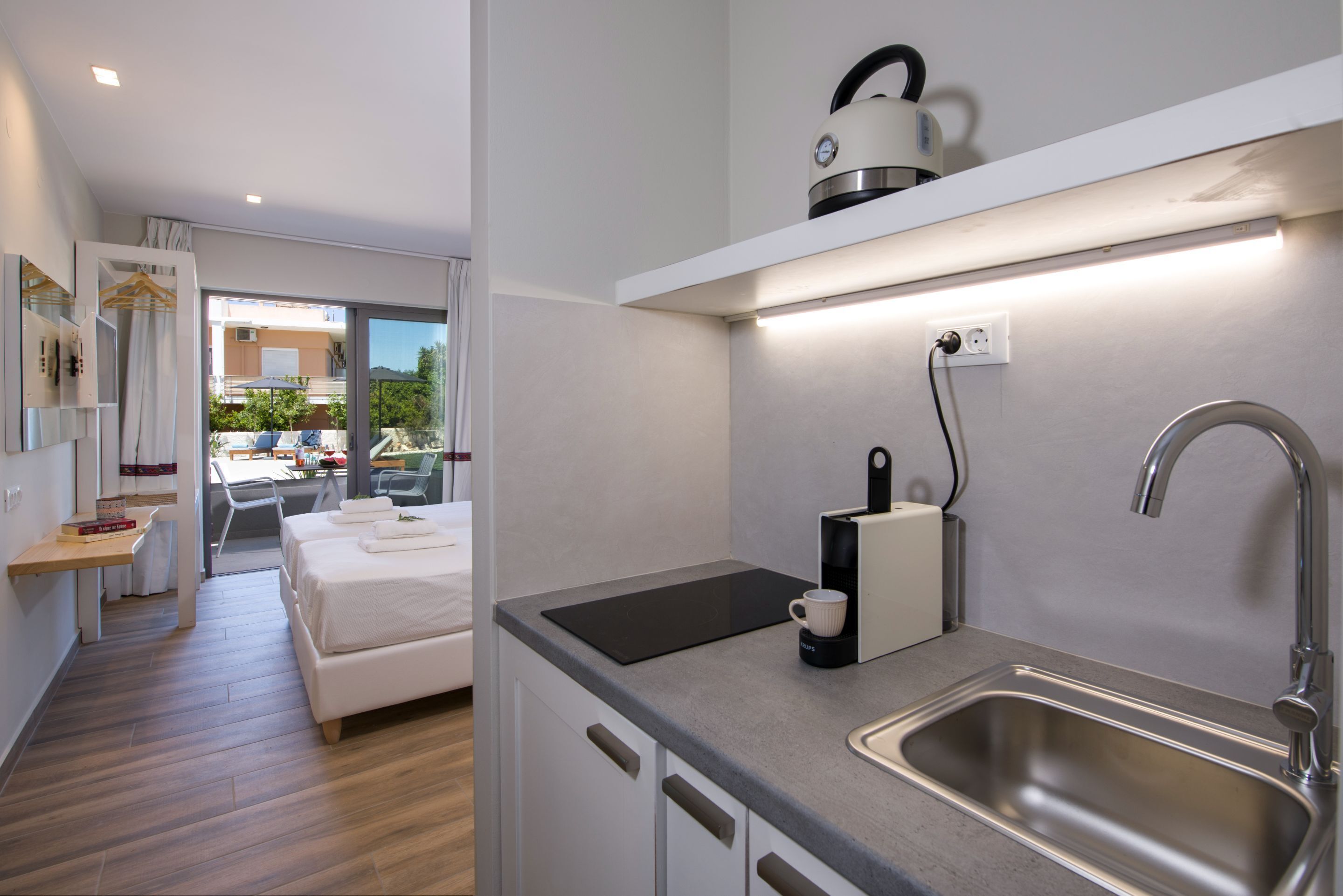 Une chambre d’hôtel moderne équipée d’une kitchenette, d’un lit, d’un coin repas avec une table et des chaises, et offrant une vue sur l’extérieur.