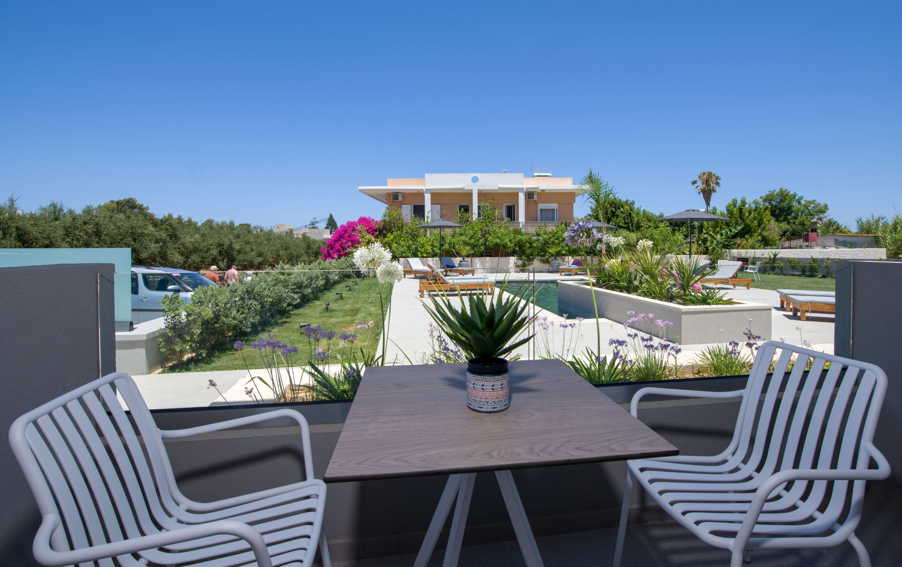 A rooftop terrace with a pool, lounge chairs, and a table with chairs.