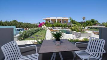 A rooftop terrace with a pool, lounge chairs, and a table with chairs.