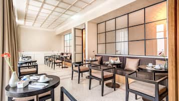 A modern hotel lobby with a seating area, tables, and a decorative wall.