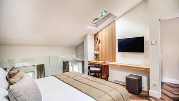 Una habitación de hotel moderna con una cama grande, un escritorio con una silla, un televisor de pantalla plana y un cubo de basura pequeño.