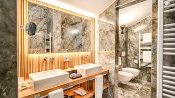 A modern bathroom with two sinks, a large mirror, wooden vanity, and a shower area.
