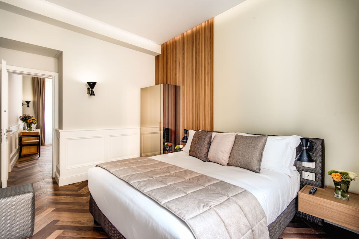 Een hotelkamer met een groot bed, een nachtkastje met een lamp en een wandlamp.