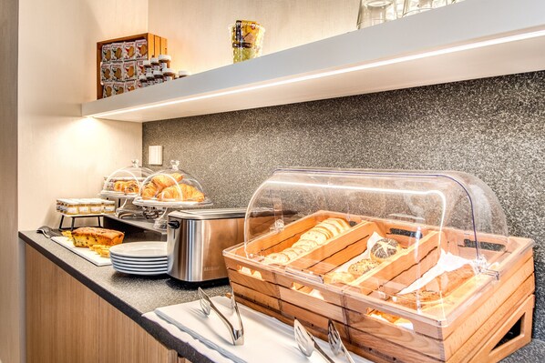 A buffet counter with various baked goods, including bread and pastries, and a selection of condiments and spreads. - DBH Duomo Boutique Hotel Lake Como (Como)