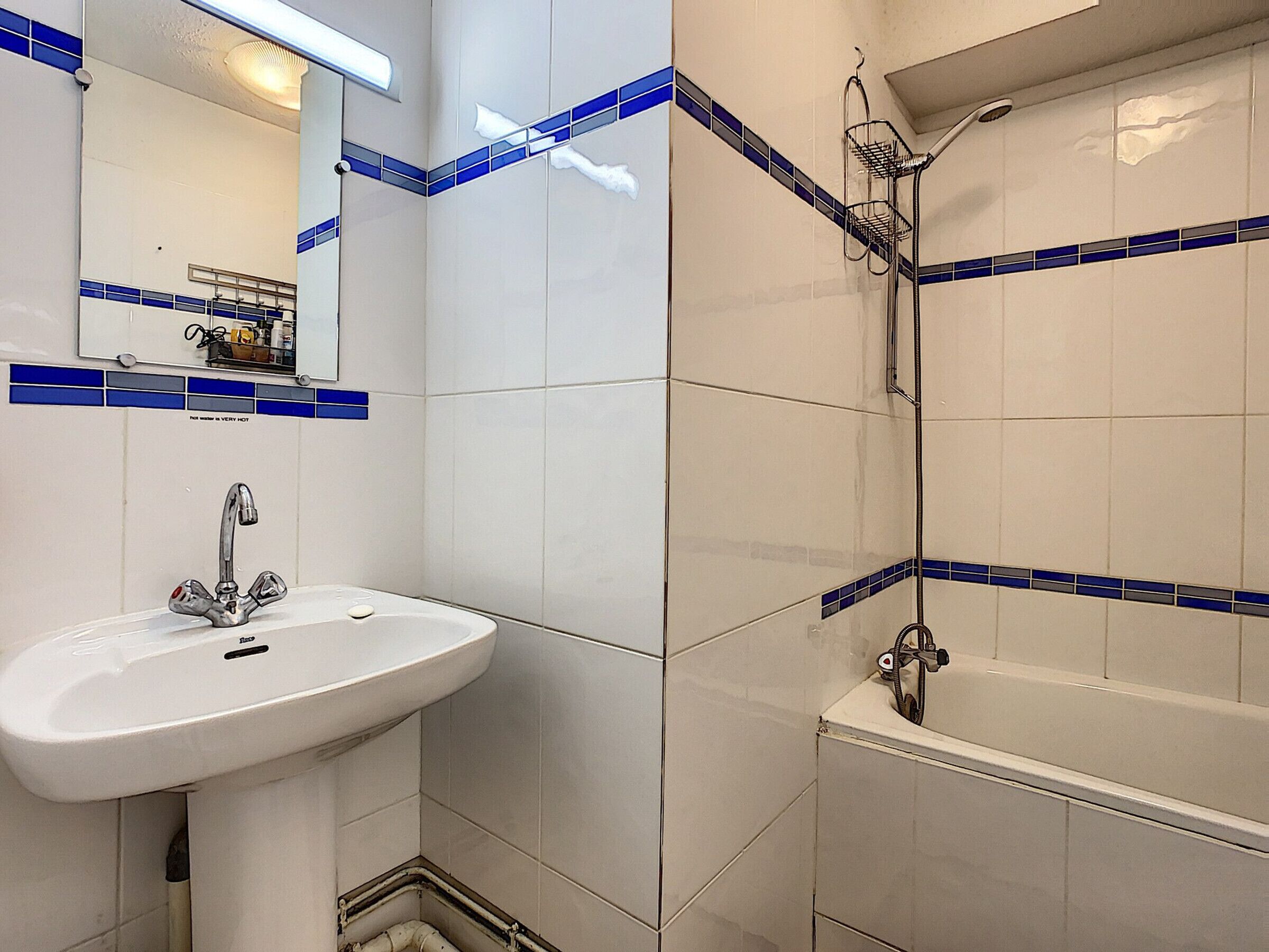Ein Badezimmer mit einem weißen Waschbecken, einem Spiegel und einer Duschkabine.