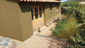 Un edificio de una planta con techo de tejas, puerta de madera y ventana.