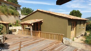 Una terraza de madera que conduce a un edificio con techo de tejas y fachada color crema.