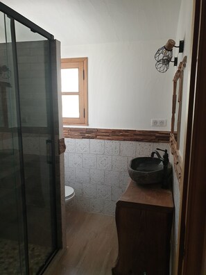 A small bathroom with a wooden sink, a window, and a toilet.