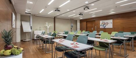 A conference room with tables, chairs, a whiteboard, and a projector screen.