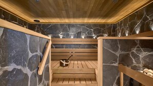 Una sauna de madera con paredes de piedra y bancos.