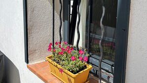 Una ventana con una jardinera amarilla que contiene flores rosadas.