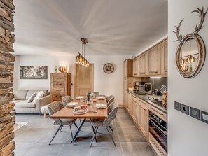 Una cucina moderna con mobili in legno, un'area pranzo con tavolo e sedie di legno, e una parete decorata con pietra.