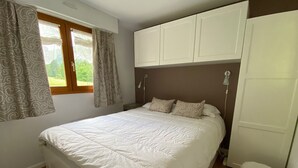 Un dormitorio con cama, cortinas, ventana y armario.