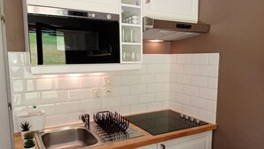 Una cocina con gabinetes blancos, un lavamanos de acero inoxidable, una estufa negra y una encimera de madera.