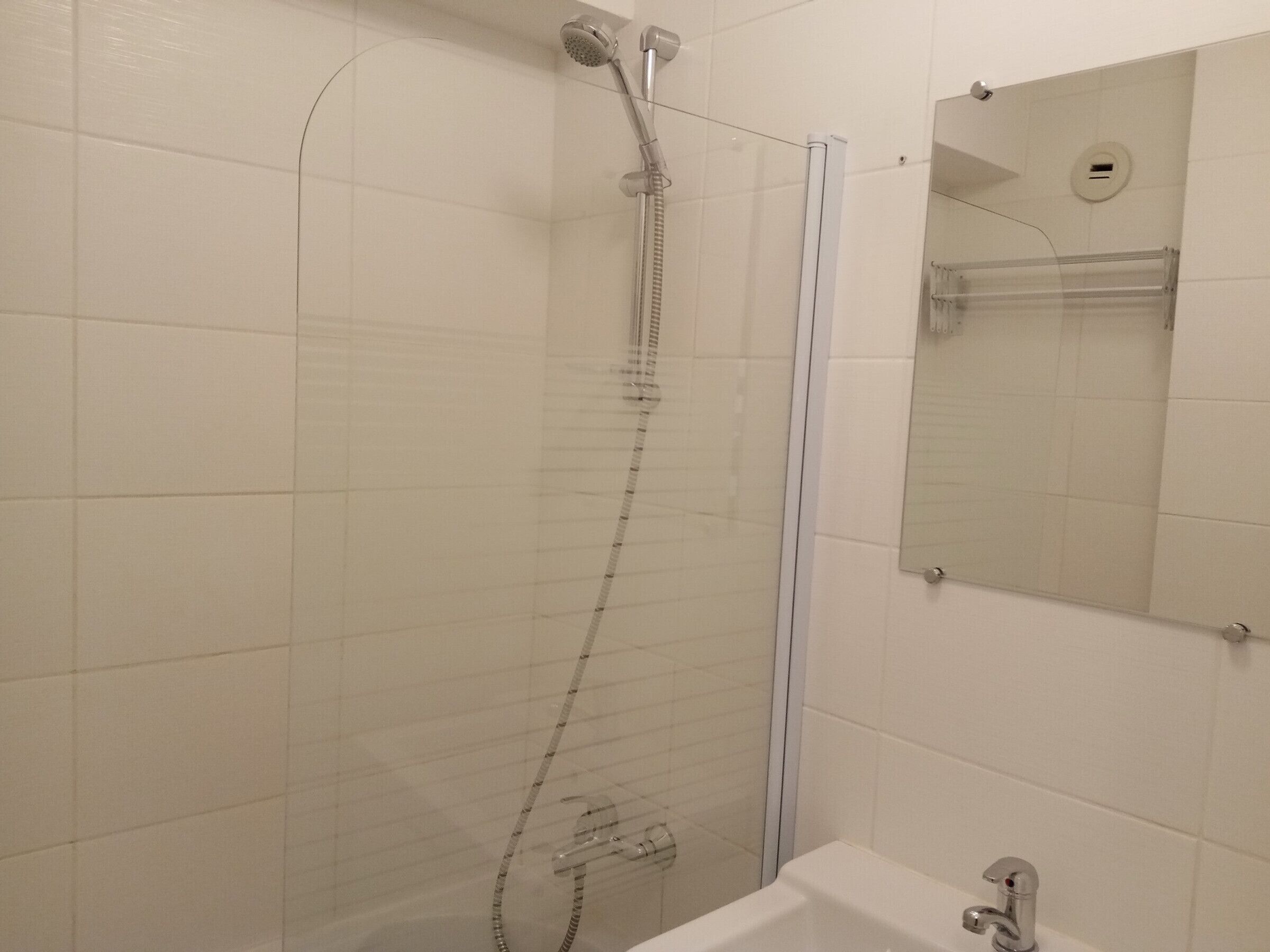 Une salle de bain avec une douche à parois de verre, une baignoire et un miroir au-dessus du lavabo.