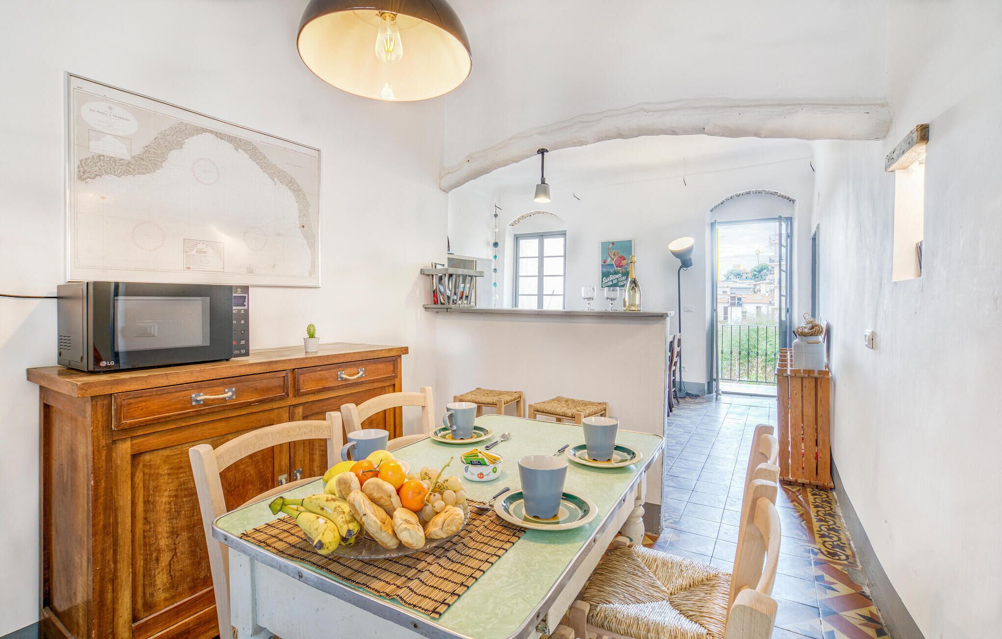 A dining area with a table set for two, a microwave on a wooden cabinet, and a map on the wall.
